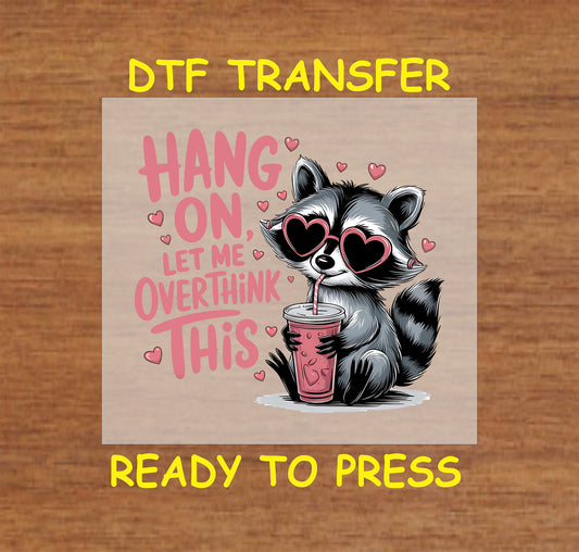 Funny raccoon DTF transfer with a cute raccoon wearing heart sunglasses and the phrase "Hang On, Let Me Overthink This."