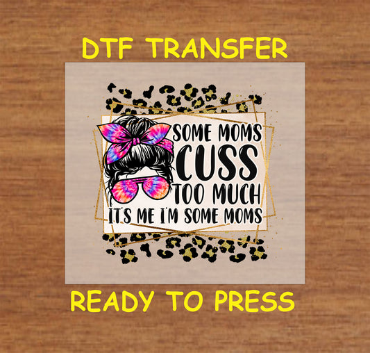 "Some Moms Cuss Too Much" DTF transfer with a messy bun, tie-dye bow, sunglasses, and leopard print background.