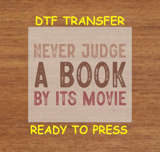 Never Judge a Book by Its Movie DTF transfer with bold distressed lettering for heat pressing.