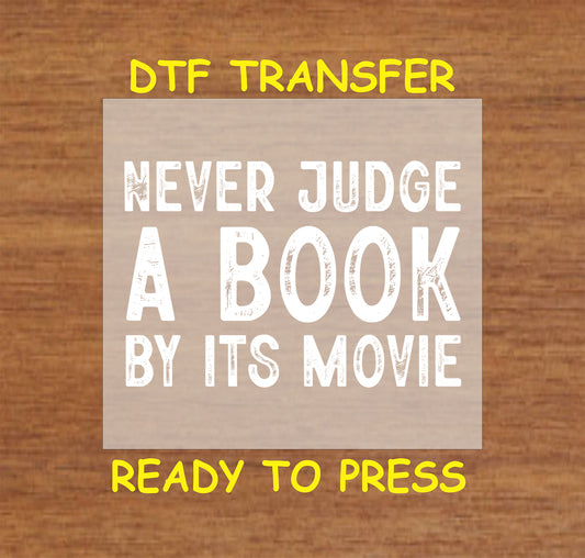 Never Judge a Book by Its Movie DTF transfer with bold distressed lettering for heat pressing.