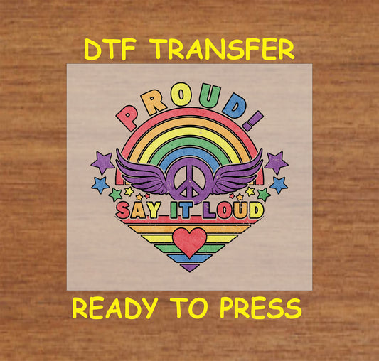 "Proud Say It Loud" rainbow heart with peace sign, wings, and stars in bright colors, perfect for custom LGBTQ+ apparel.