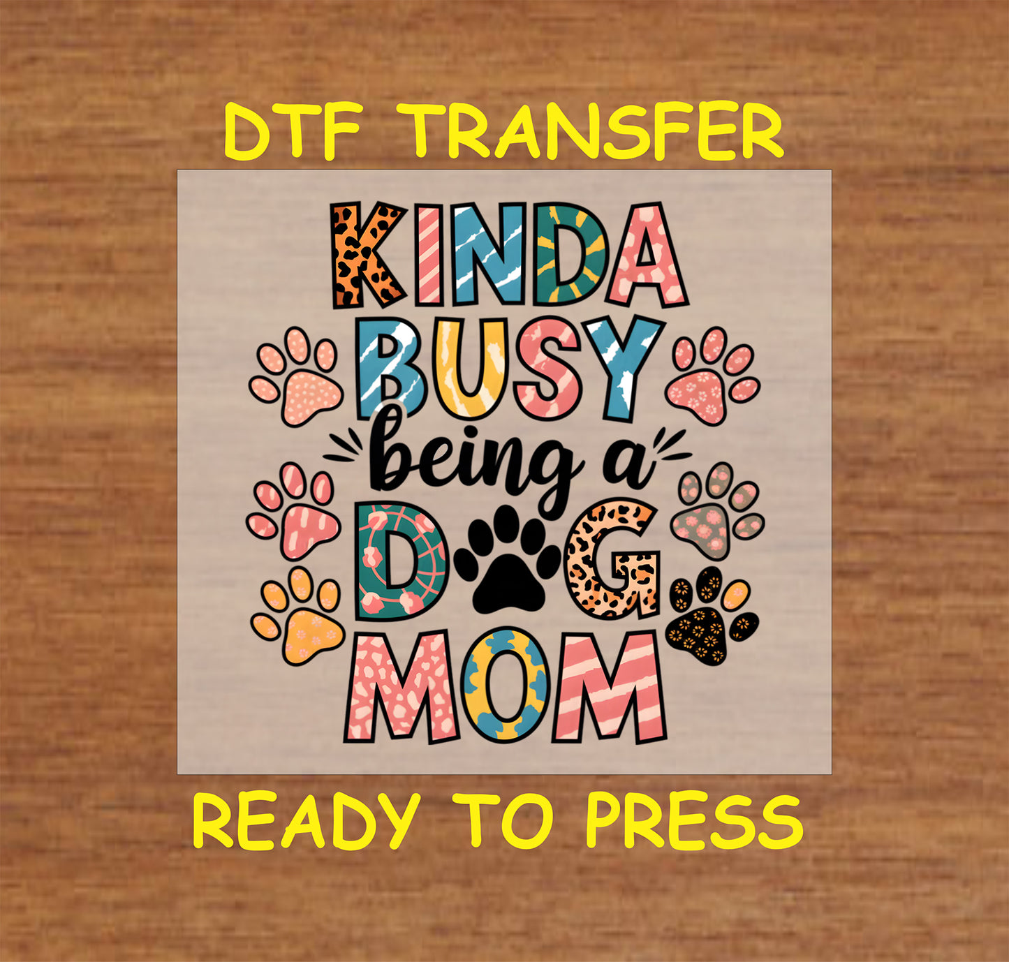 Kinda Busy Being a Dog Mom DTF transfer with multicolor text and paw prints.