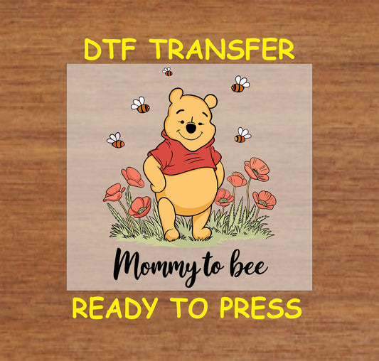 Cartoon bear with bees and poppy flowers above the phrase "Mommy to bee"