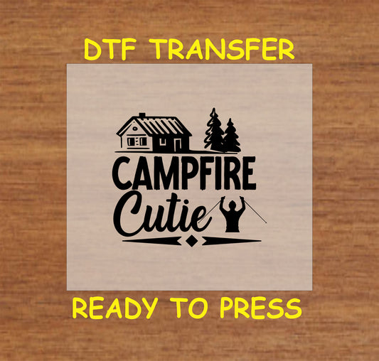 Campfire Cutie with cabin, pine trees, and marshmallow roasting silhouette, ready-to-press DTF transfer.