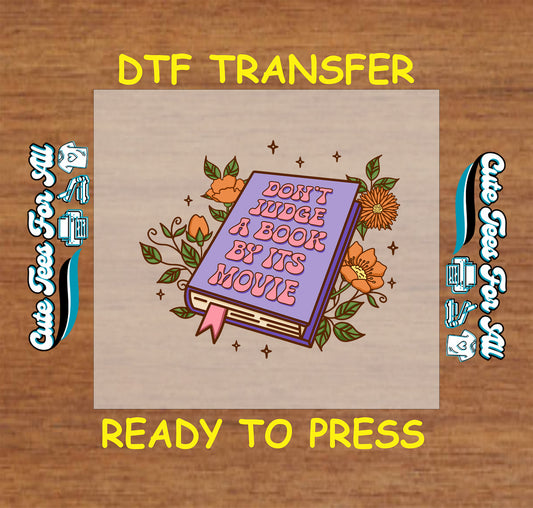 DTF transfer with purple book, orange flowers, and the quote “Don’t judge a book by its movie”