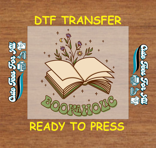 DTF transfer with open book, wildflowers, stars, and the word "Bookaholic" in green retro font.