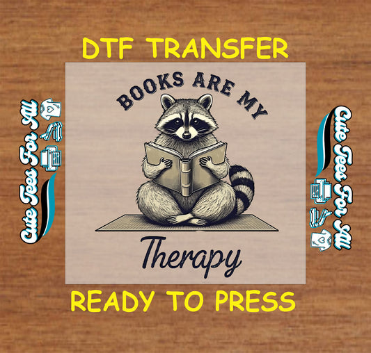 DTF transfer with raccoon sitting and reading a book with “Books Are My Therapy” text.