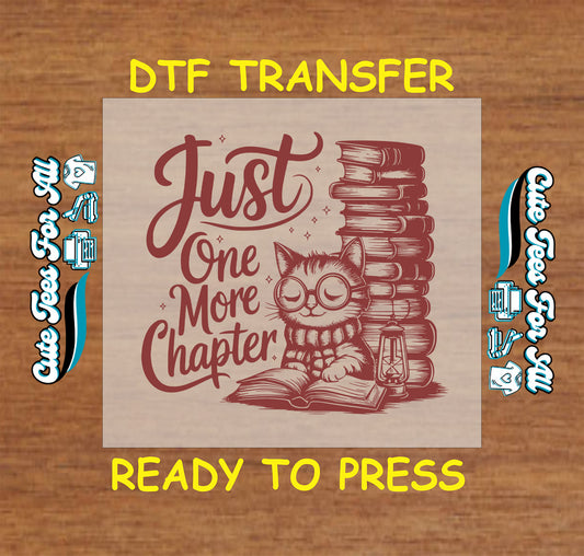 DTF transfer with cat in glasses reading a book beside a tall stack of books and the words “Just One More Chapter”