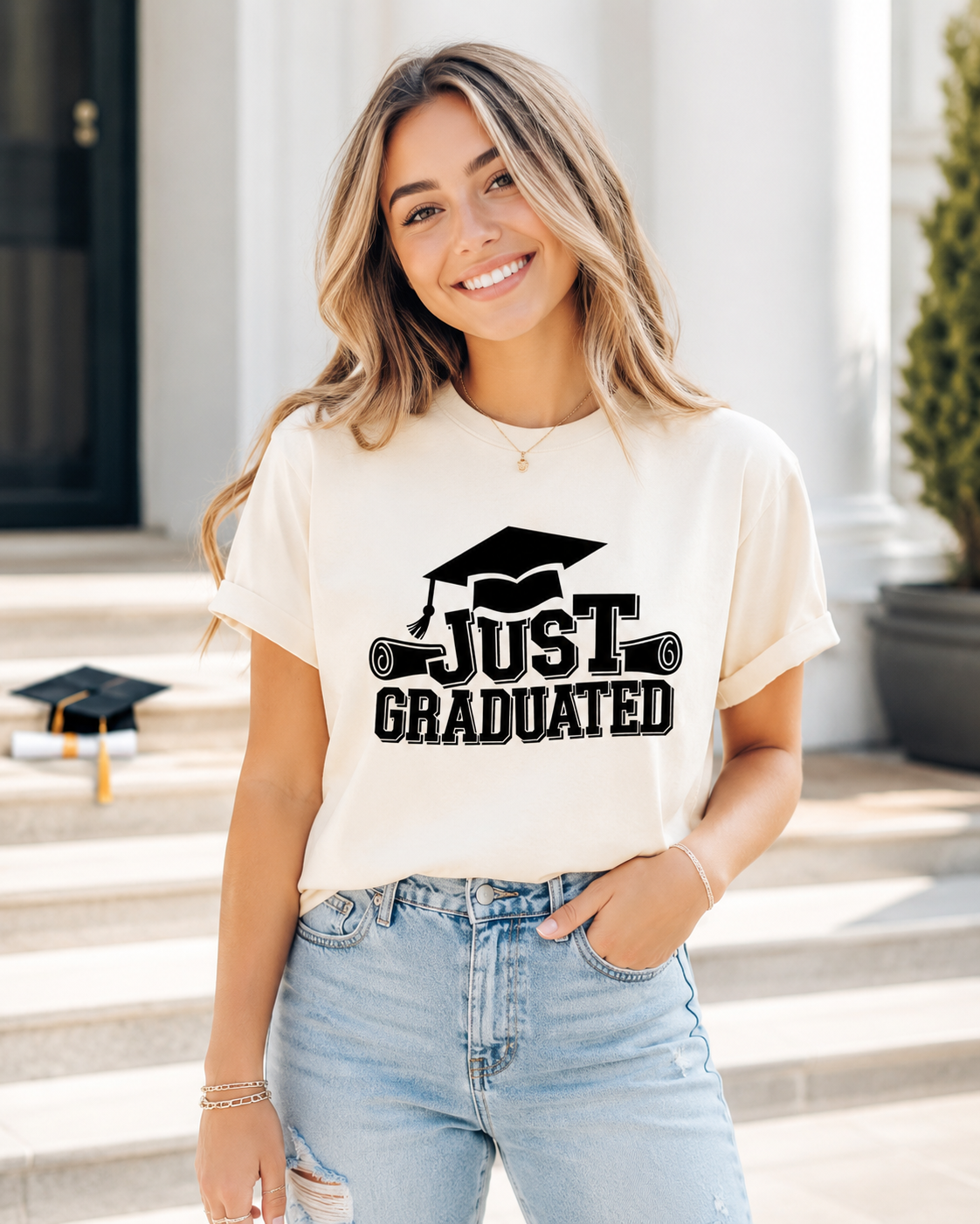 Cream shirt mockup featuring a graduation ready to press dtf transfer with the phrase Just Graduated, varsity lettering, cap, and diploma graphics.