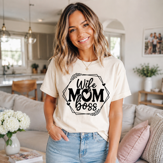 Lifestyle mockup of a cream shirt featuring a black Wife Mom Boss ready to press dtf graphic with hearts, leopard accents, and geometric frame.
